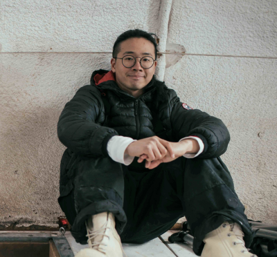 Aaron poses in fieldwork gear in a white-walled building 