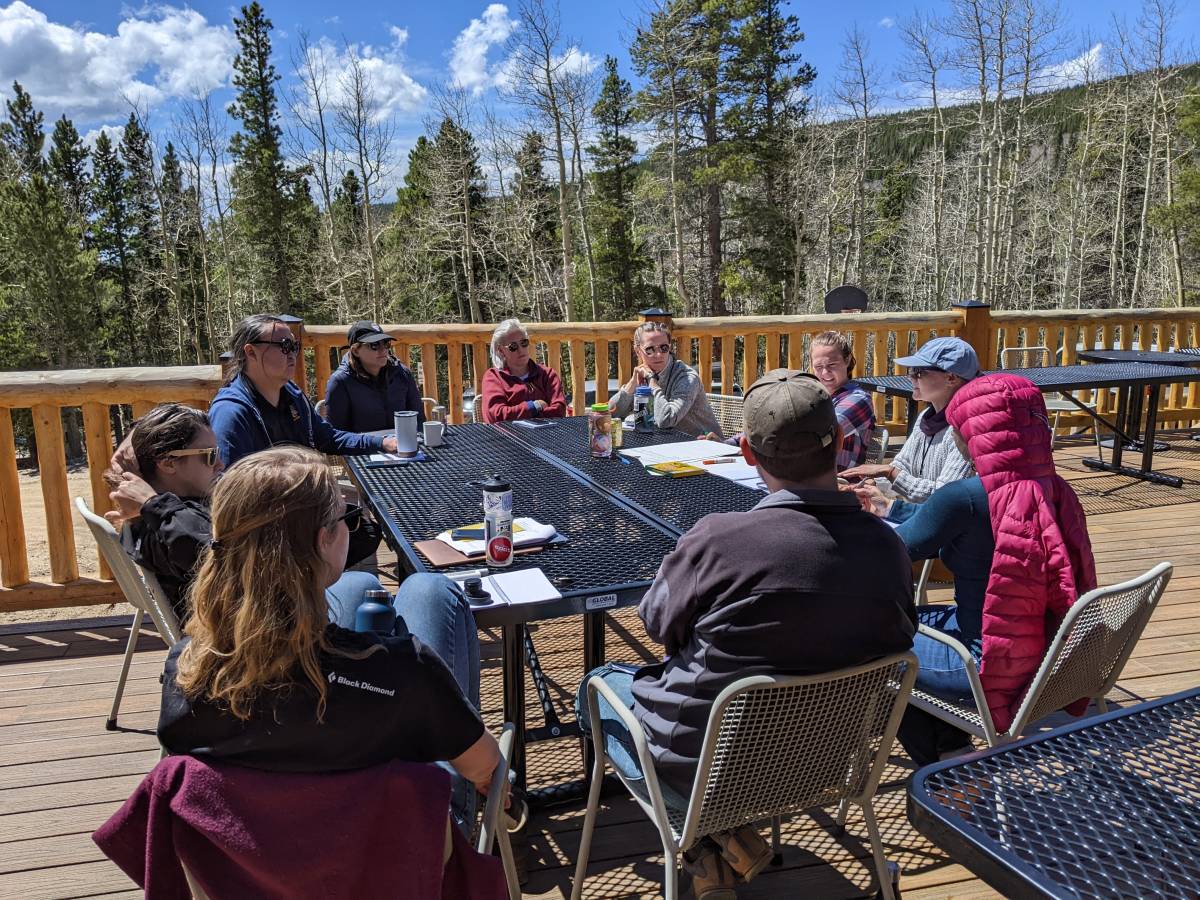 A GROUP OF PARTICIPANTS DICUSS PROPOSAL IDEAS OUTSIDE AT THE MOUNTAIN RESEARCH STATION. PHOTO: BEC BATCHELOR/CIRES.