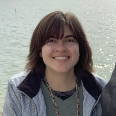 Madison Payne smiles at the camera, with water in the background