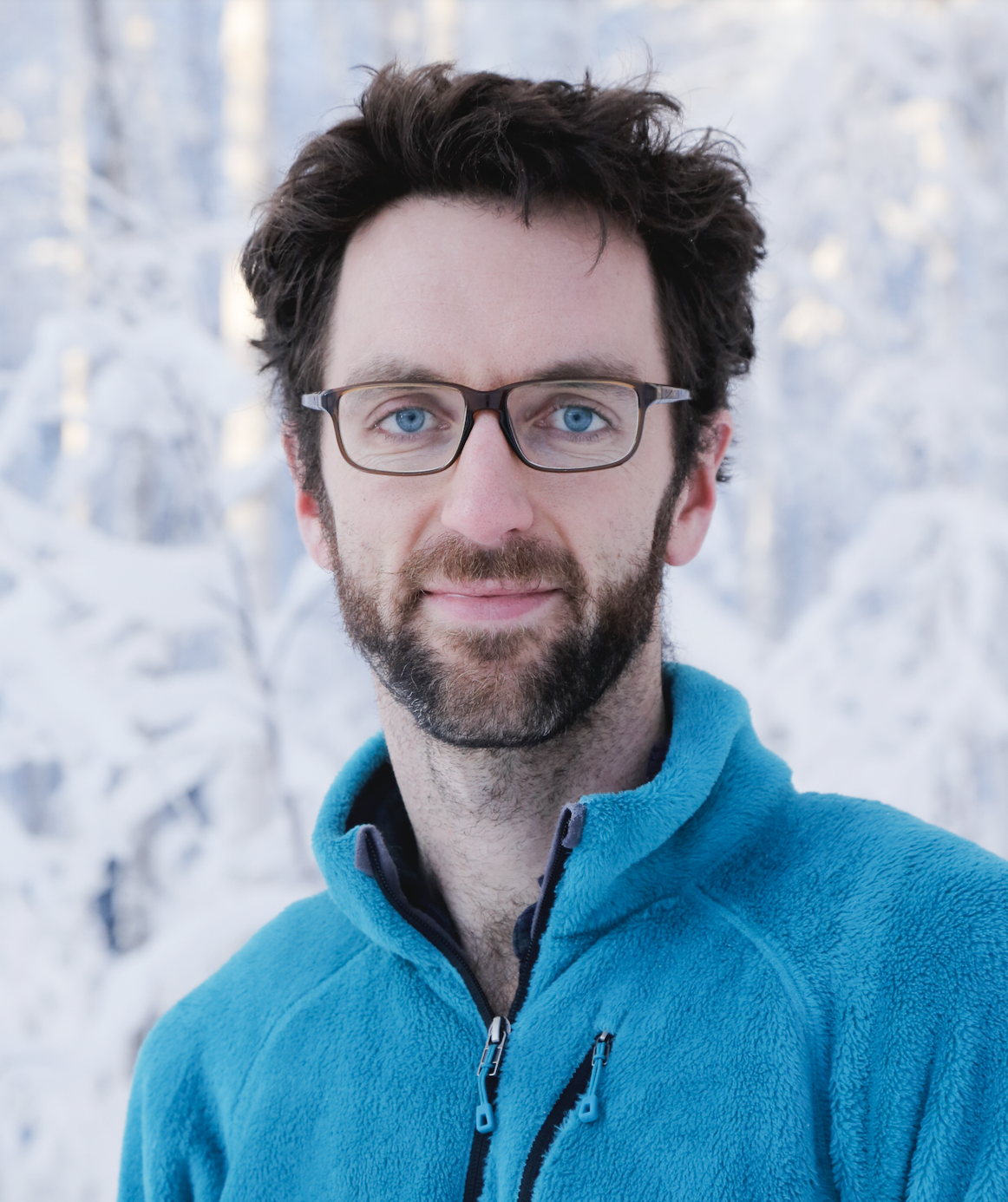 Wil Burt smiles for the camera in front of a snowy scene