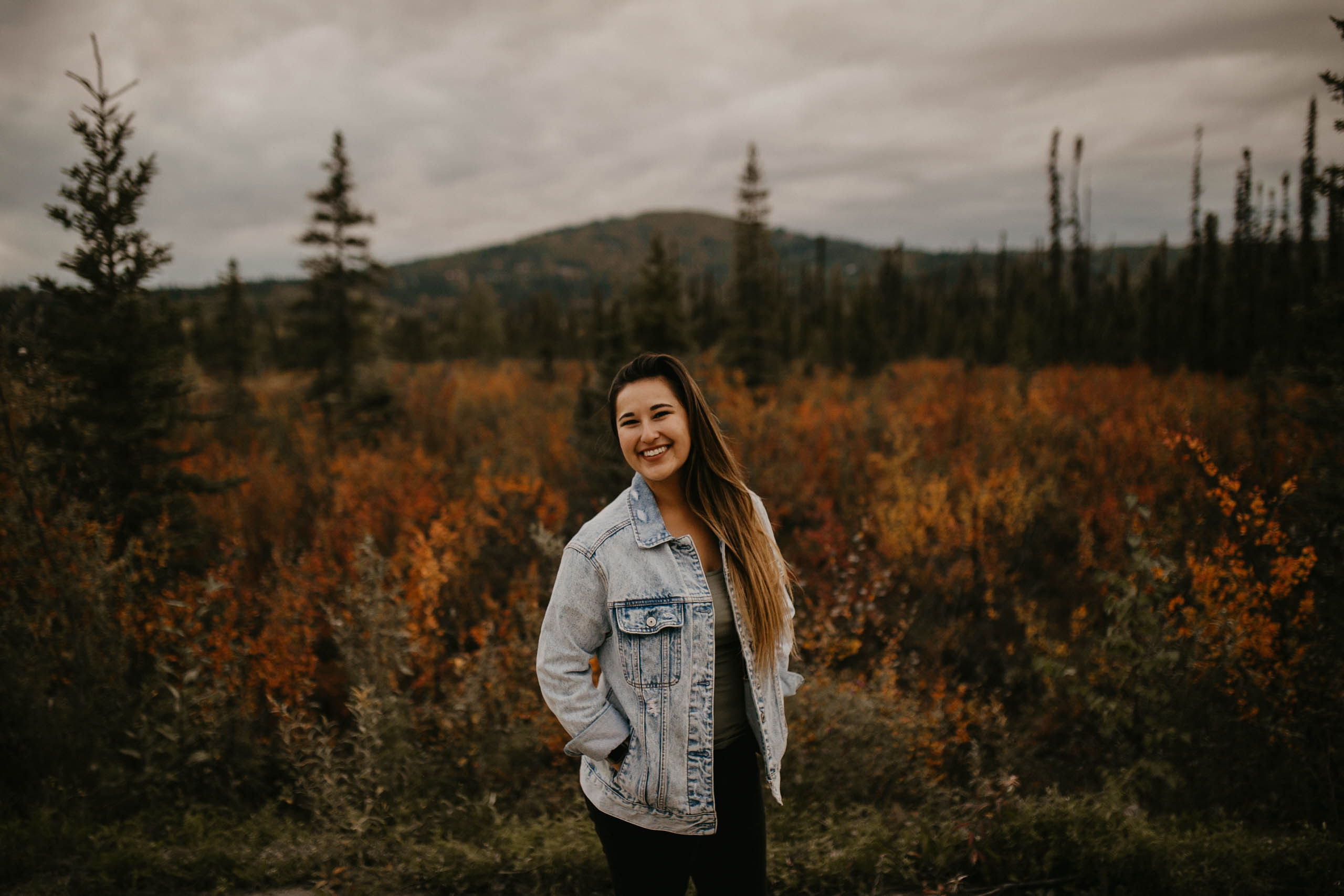 Darcy Peter looks at the camera with a fall Alaskan scene in the background.