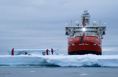 Scientists on an ice floe with an Icebreaker in the background