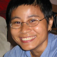 Person in a blue shirt and glasses. Close up headshot photo.